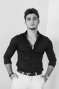Monochrome portrait of a stylish young man posing confidently indoors.